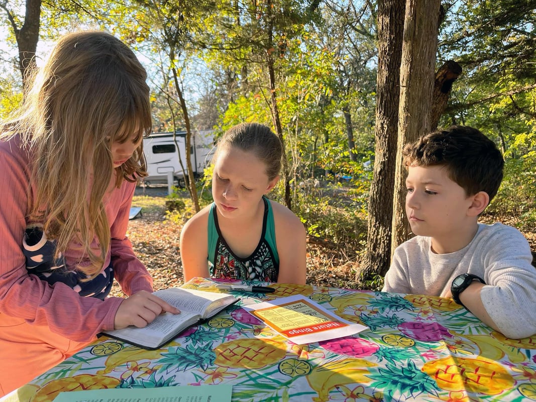 Three children reading together outside.